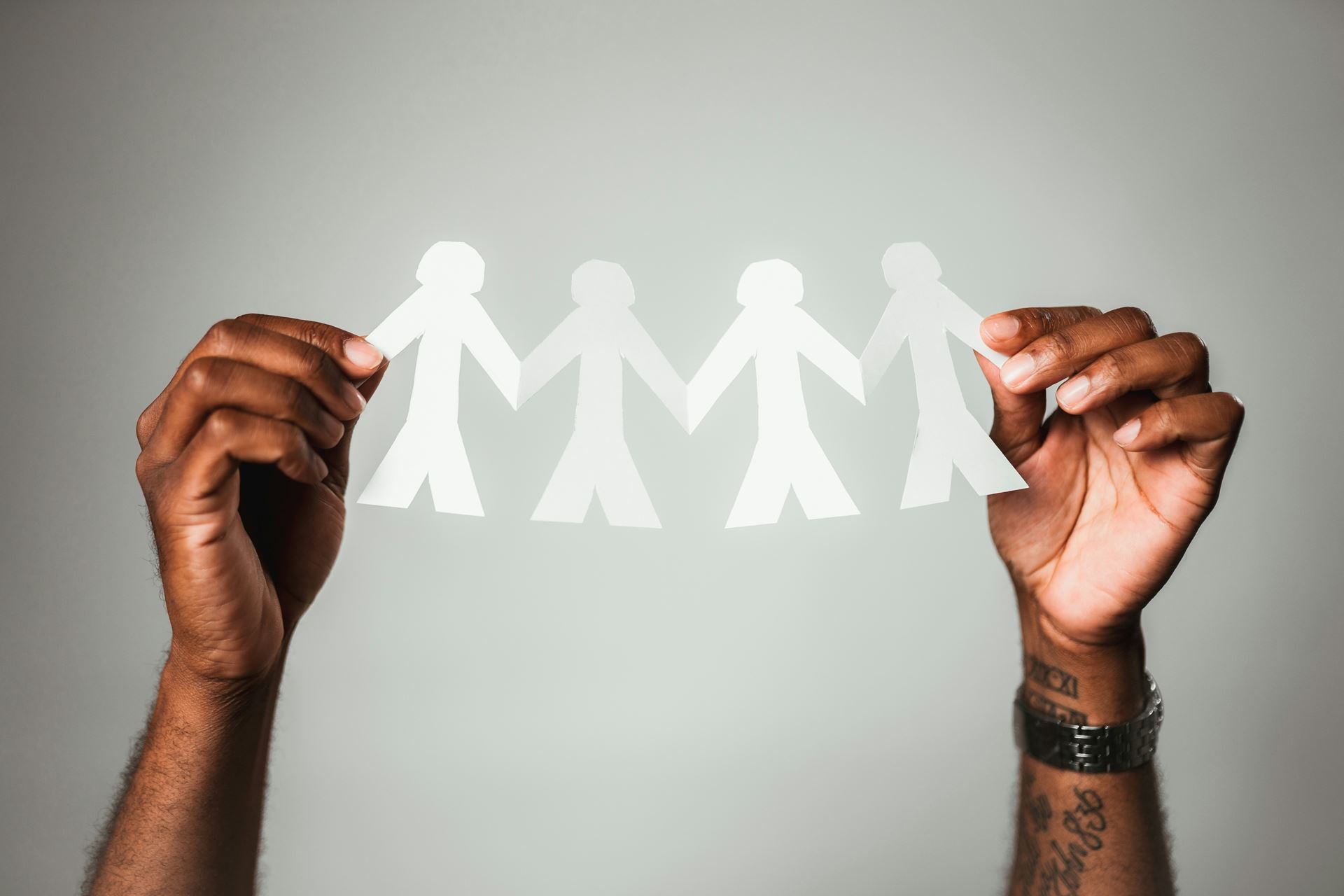 two hands holding paper chain cut out in the shape of people